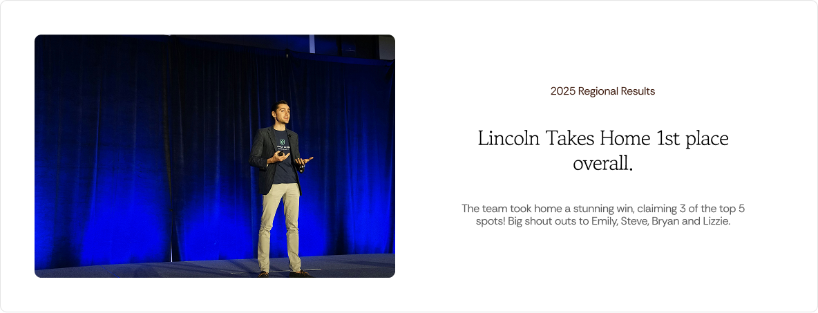 Photo of a man giving a talk on stage with blue curtains behind him